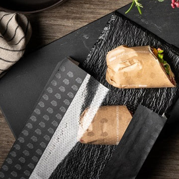 Sacchetto nero con finestra termosaldabile  su tavolino con panini